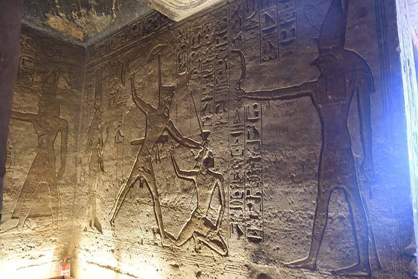 39 MAK_6562.jpg - Sulle pareti vari bassorilievi tra cui il faraone Ramses II nell'atto cerimoniale di abbattere i nemici dell'Egitto. Alla destra il dio Horus che porge al re la "spada della vittoria", legittimando il suo operato.